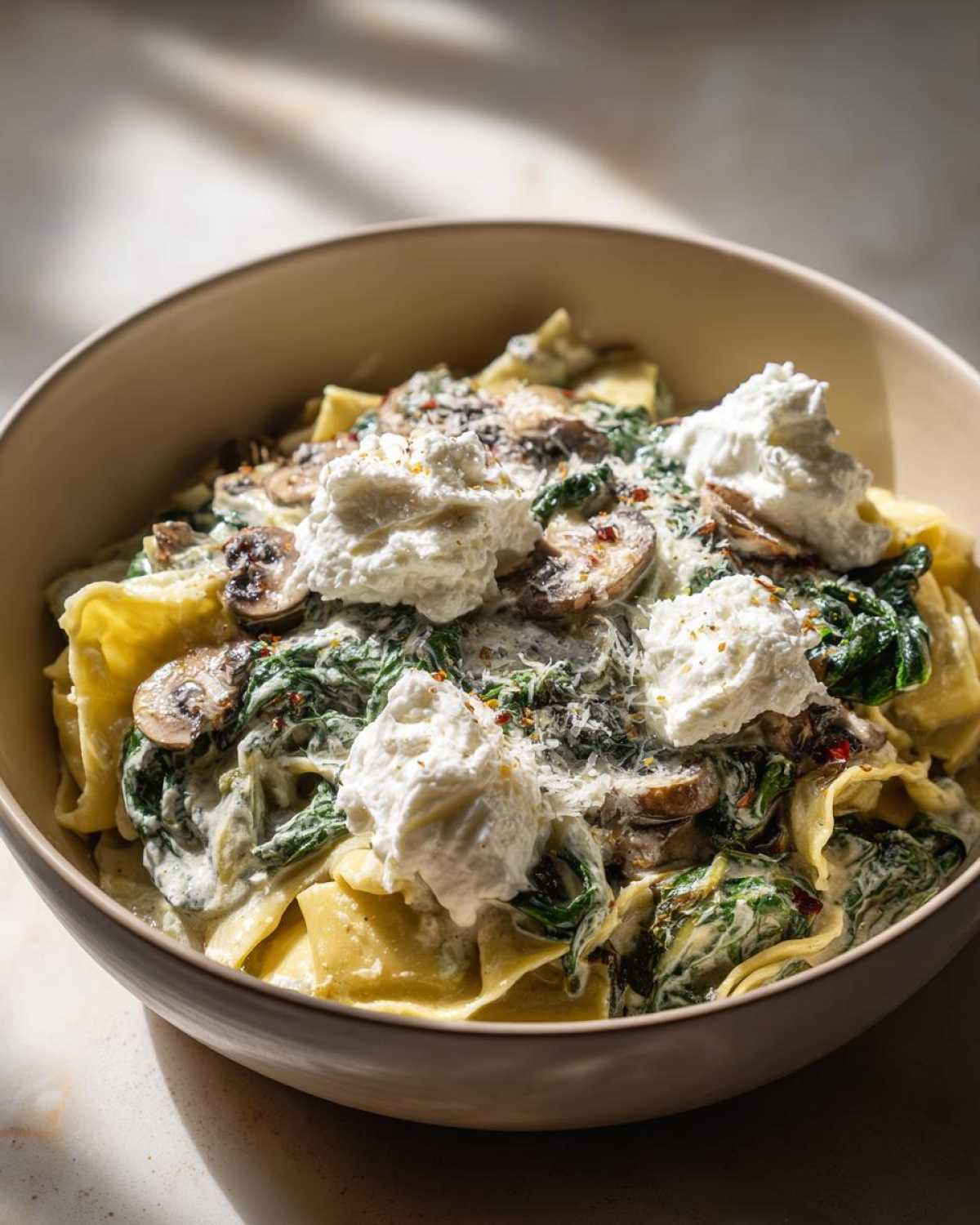 A close-up bowl of One-Pot Creamy Spinach Mushroom Lasagna Soup topped with dollops of ricotta cheese.