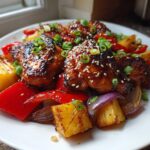 Glazed Sheet Pan Teriyaki Chicken Thighs with pineapple, red peppers, and onions, garnished with sesame seeds.