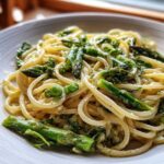 A close-up of creamy Vegan Lemon Asparagus Pasta tossed with bright green asparagus spears and peas.