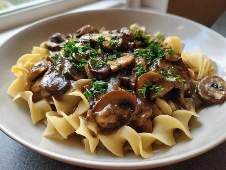 Close-up of Vegan Mushroom Stroganoff served over wide egg noodles and garnished with fresh parsley.