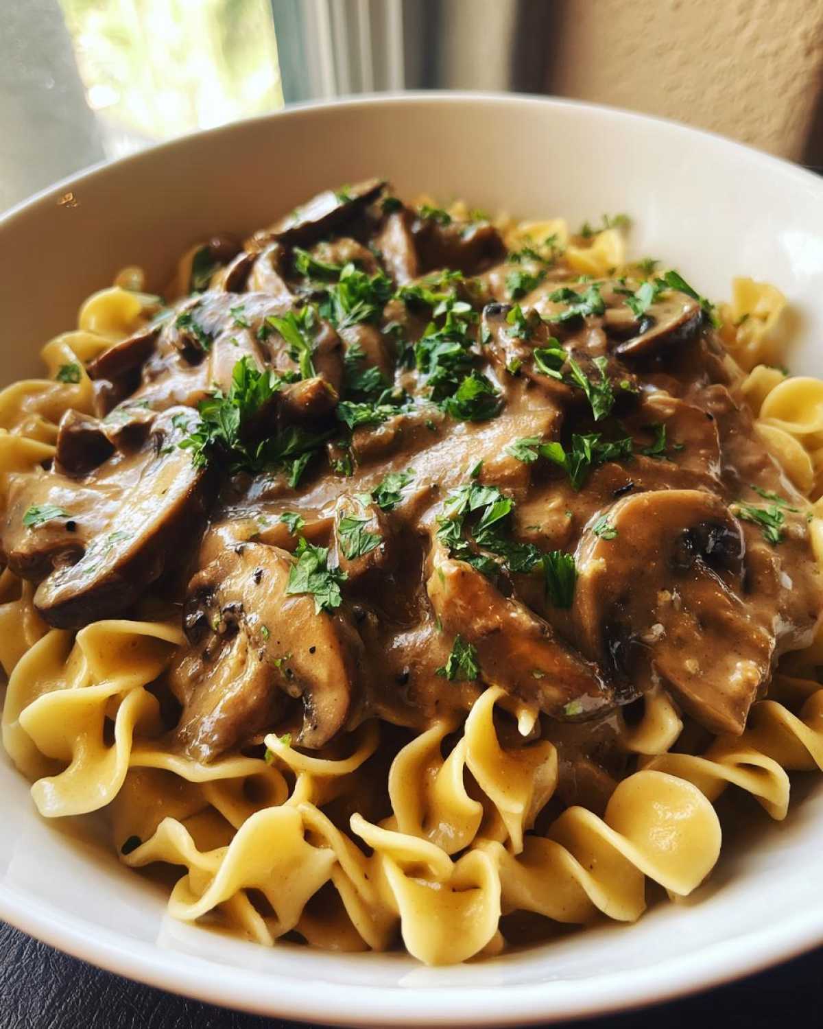Close-up of Vegan Mushroom Stroganoff served over egg noodles and garnished with fresh parsley.