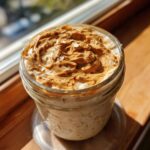 Close-up of Vegan Peanut Butter Banana Overnight Oats topped with swirled peanut butter in a glass jar.