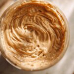 Overhead close-up of creamy, swirled peanut butter mixture being prepared for Vegan Peanut Butter Banana Overnight Oats.